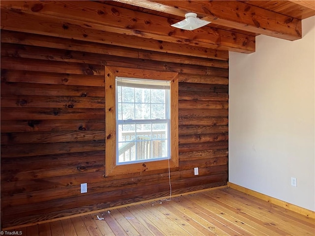 unfurnished room with beam ceiling and light hardwood / wood-style floors