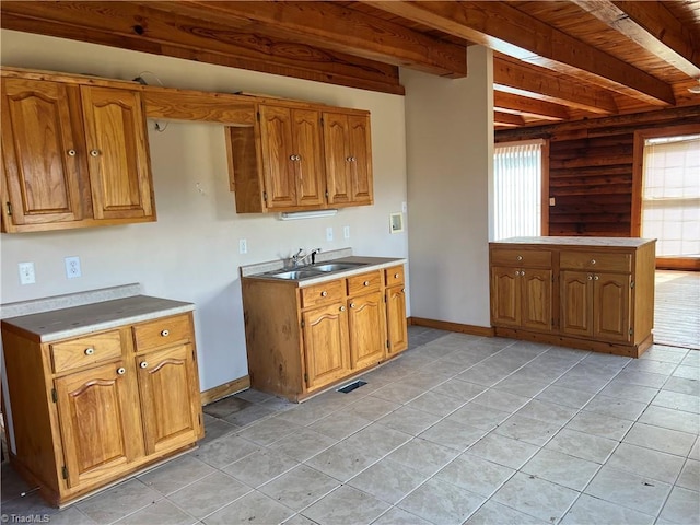 kitchen with sink, beam ceiling, wooden ceiling, and light tile patterned floors