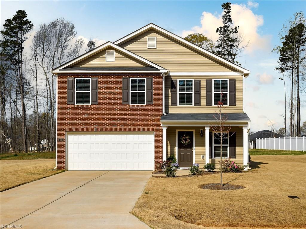 view of front facade featuring driveway, fence, a garage, and a front lawn
