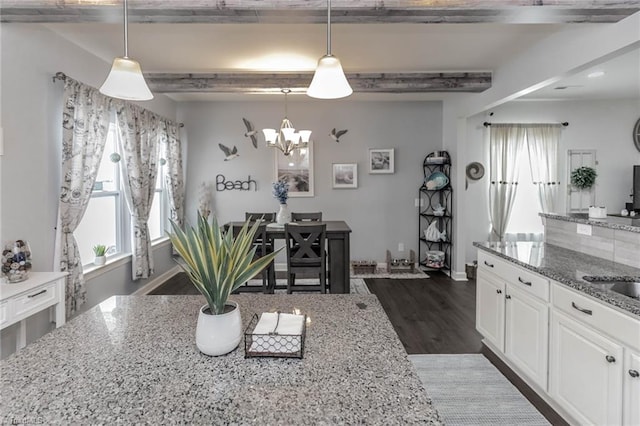 kitchen with dark wood-style floors, light stone counters, a notable chandelier, white cabinetry, and beamed ceiling