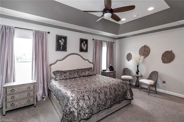 bedroom with light carpet, a tray ceiling, a ceiling fan, and baseboards