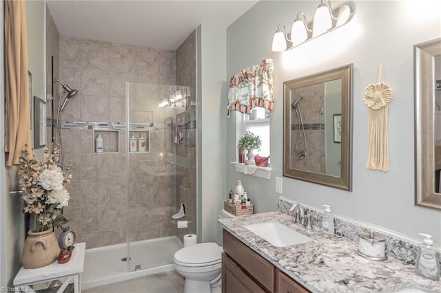 full bathroom featuring a sink, a shower stall, toilet, and double vanity