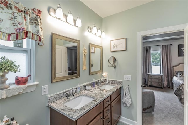 ensuite bathroom featuring double vanity, baseboards, a sink, and ensuite bathroom