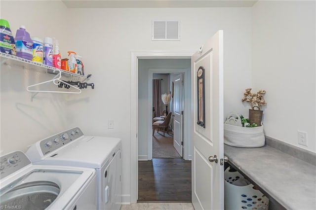 clothes washing area with laundry area, visible vents, light wood-style floors, and washing machine and clothes dryer