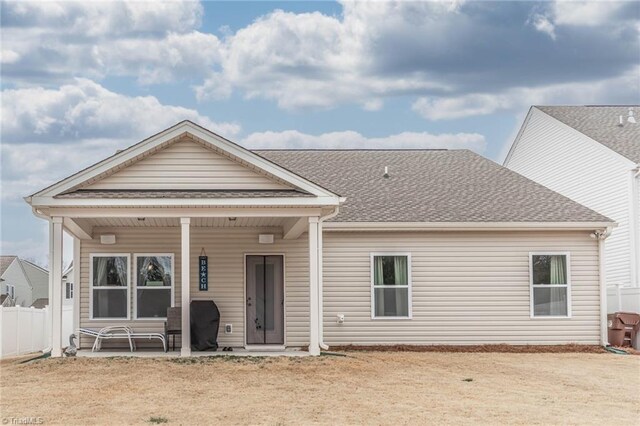 back of property featuring a shingled roof, a patio area, and fence