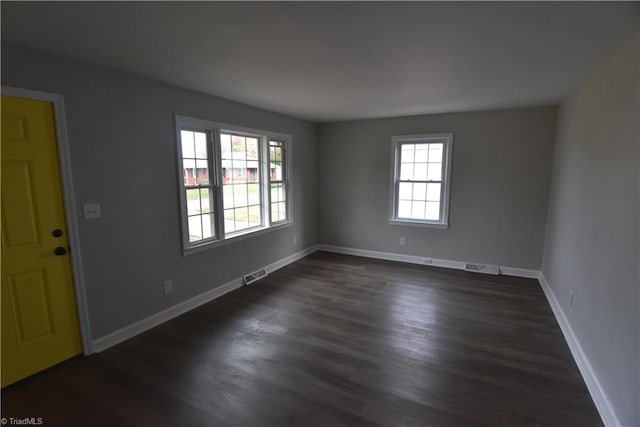 spare room with a wealth of natural light and dark hardwood / wood-style floors