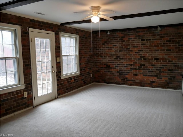 spare room with brick wall, carpet flooring, a wealth of natural light, and ceiling fan