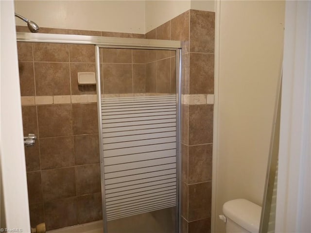 bathroom with a shower with door and toilet