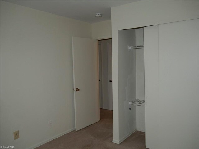 unfurnished bedroom with light colored carpet and a closet