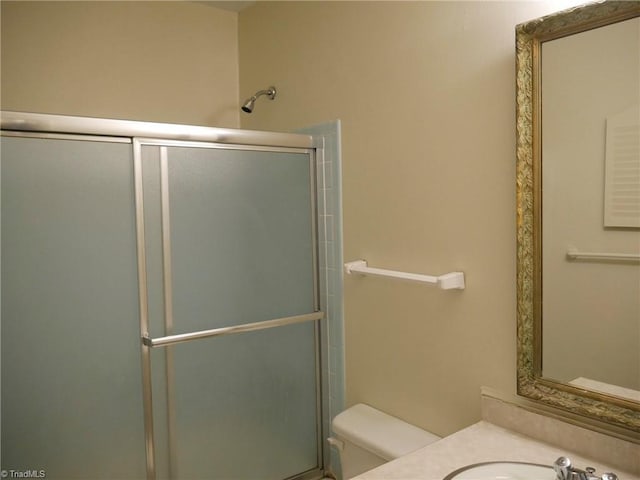 bathroom with toilet, a shower with shower door, and sink