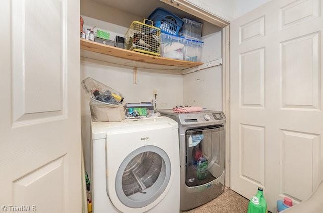 clothes washing area featuring washing machine and clothes dryer and carpet flooring