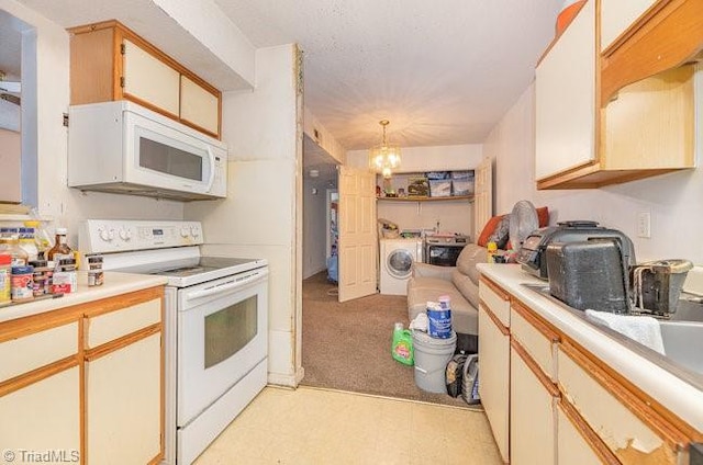 kitchen featuring white appliances, washing machine and dryer, hanging light fixtures, white cabinetry, and an inviting chandelier