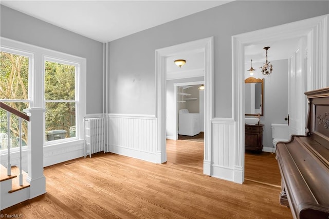 unfurnished dining area featuring washer / clothes dryer, radiator, light hardwood / wood-style floors, and sink