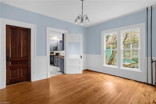 unfurnished dining area with an inviting chandelier, radiator, and hardwood / wood-style floors