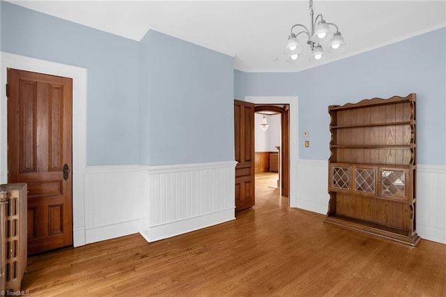 empty room featuring radiator heating unit, a chandelier, and hardwood / wood-style floors