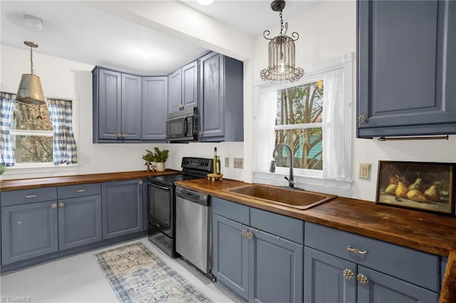 kitchen with sink, stainless steel dishwasher, wood counters, and decorative light fixtures