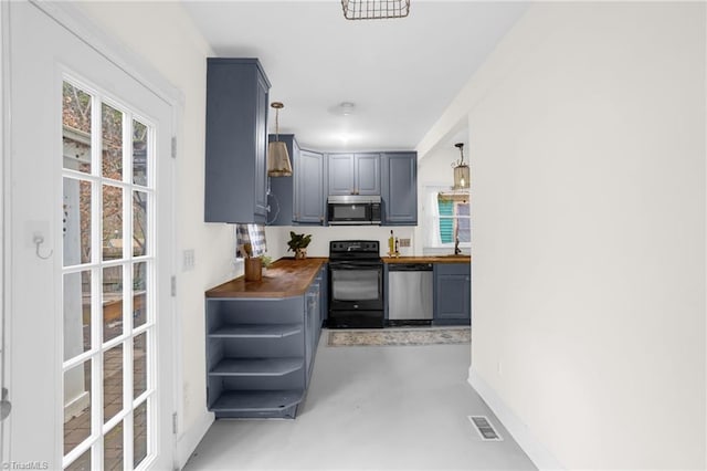 kitchen featuring appliances with stainless steel finishes, sink, butcher block countertops, and decorative light fixtures