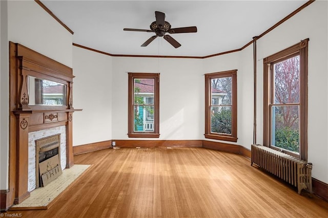 unfurnished living room with a premium fireplace, ornamental molding, radiator, and light hardwood / wood-style floors