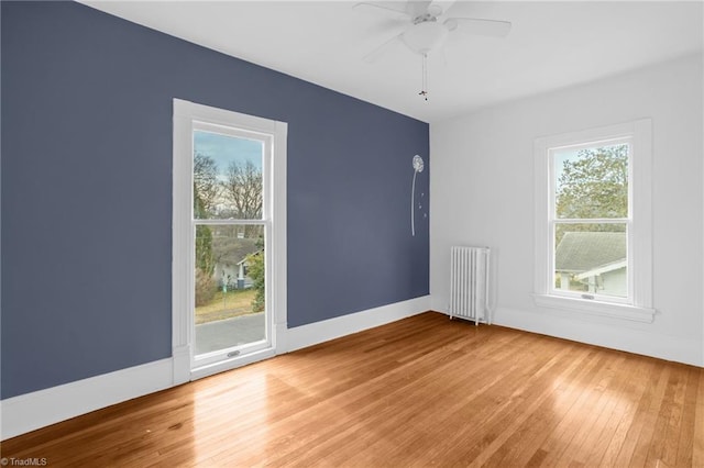 spare room with ceiling fan, radiator heating unit, and hardwood / wood-style floors