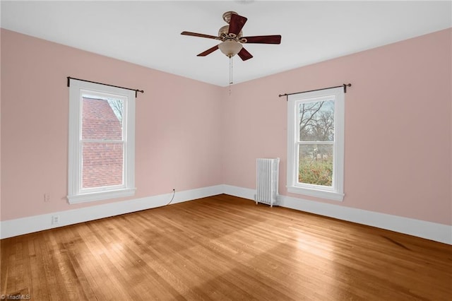 empty room with radiator heating unit, ceiling fan, and light wood-type flooring