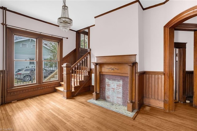 stairs featuring crown molding, wooden walls, hardwood / wood-style floors, and an inviting chandelier