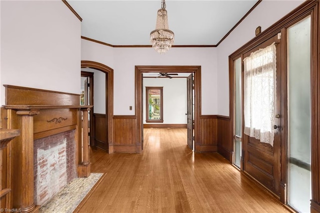 interior space with an inviting chandelier, ornamental molding, light hardwood / wood-style floors, and wood walls