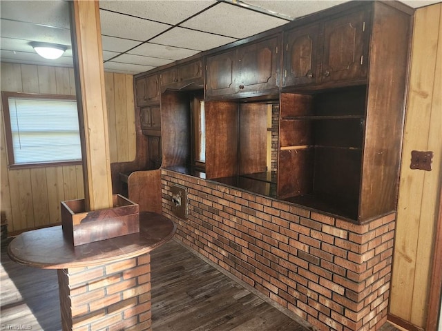 bar with a drop ceiling, wood walls, dark brown cabinets, and dark hardwood / wood-style flooring