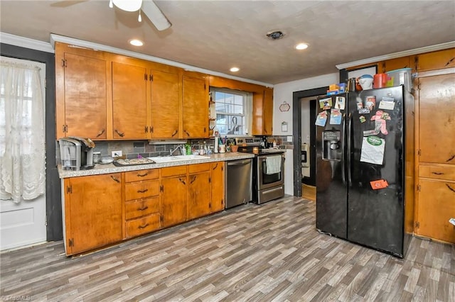 kitchen with sink, crown molding, light wood-type flooring, appliances with stainless steel finishes, and tasteful backsplash