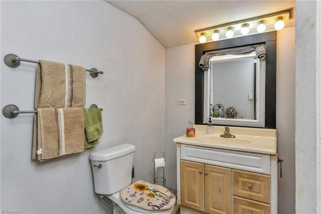 bathroom featuring vanity, toilet, and lofted ceiling