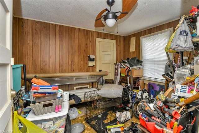 miscellaneous room with wood walls, ceiling fan, and a textured ceiling