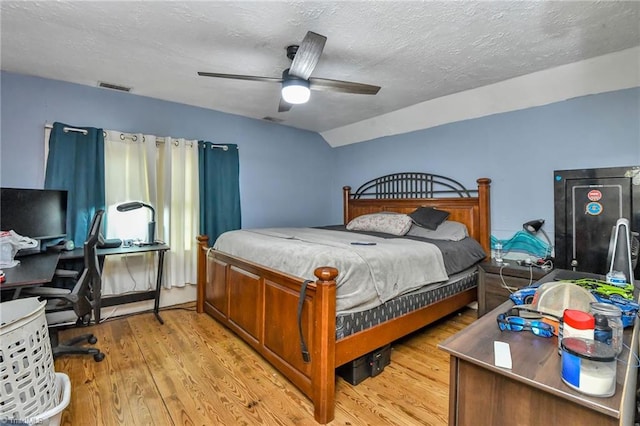 bedroom with a textured ceiling, light wood-type flooring, ceiling fan, and lofted ceiling