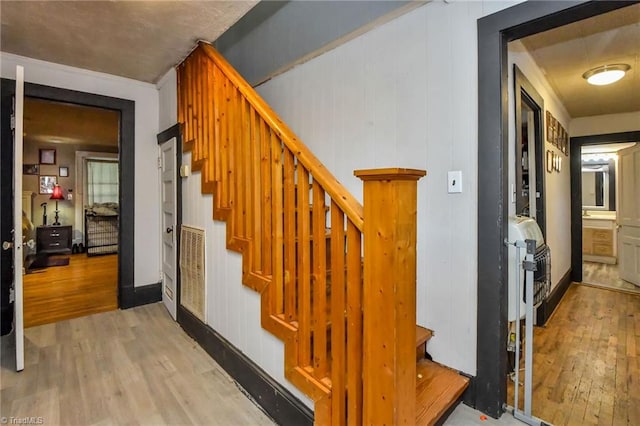 stairway with wooden walls and hardwood / wood-style flooring