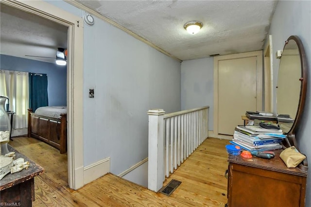 corridor with a textured ceiling and light hardwood / wood-style floors
