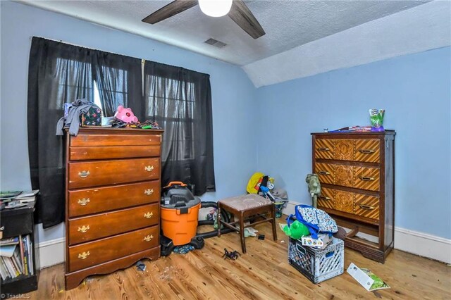 bedroom with wood-type flooring, a textured ceiling, ceiling fan, and lofted ceiling