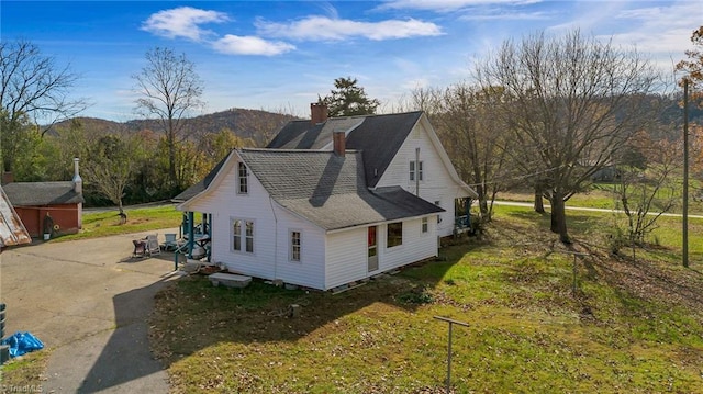 view of side of property with a mountain view and a yard