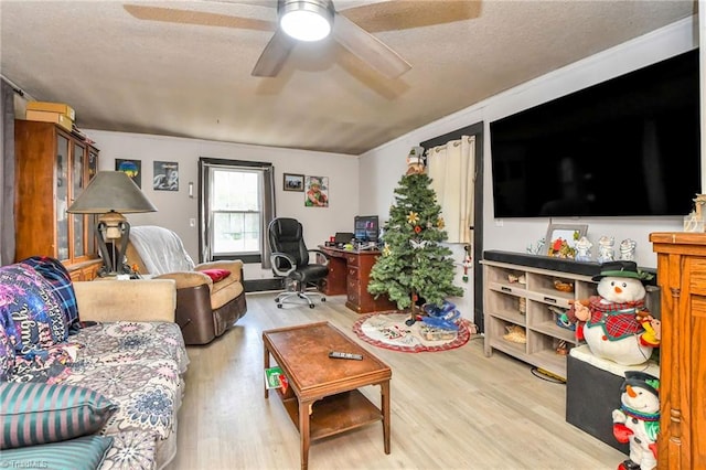 living room featuring ceiling fan, light hardwood / wood-style flooring, crown molding, and a textured ceiling