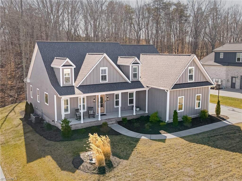 view of front of house with cooling unit, a front lawn, and covered porch