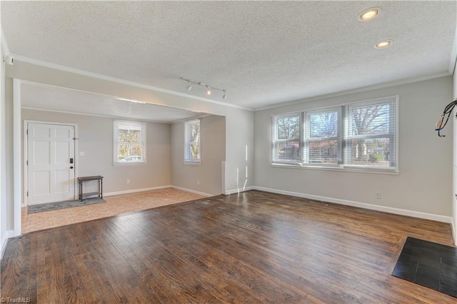 unfurnished living room with dark hardwood / wood-style floors, ornamental molding, track lighting, and a textured ceiling