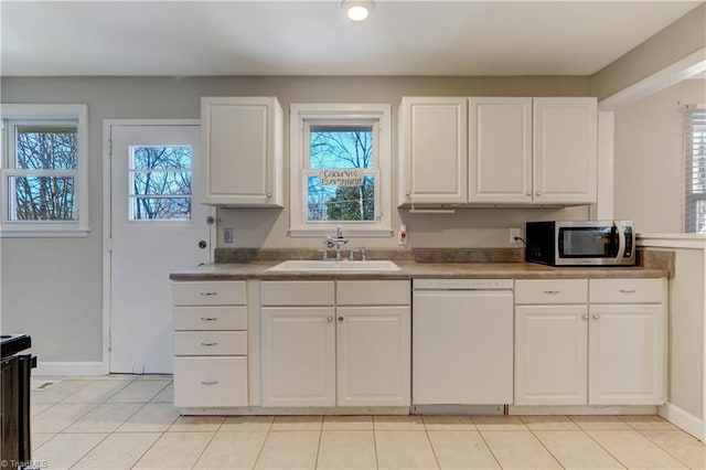 kitchen featuring light tile patterned floors, dishwasher, sink, and white cabinetry