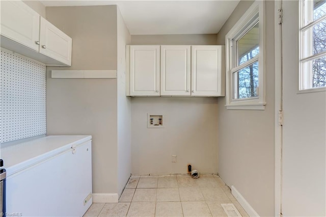 clothes washing area featuring light tile patterned floors, hookup for a washing machine, and cabinets