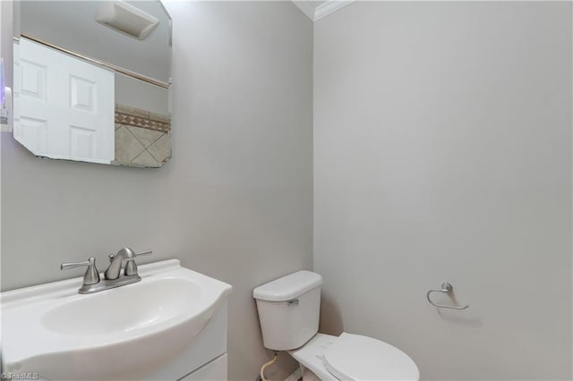 bathroom featuring toilet, vanity, and crown molding