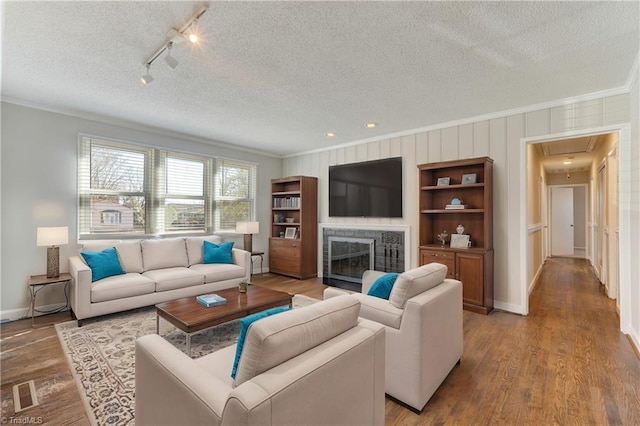 living room with a textured ceiling, crown molding, and light wood-type flooring