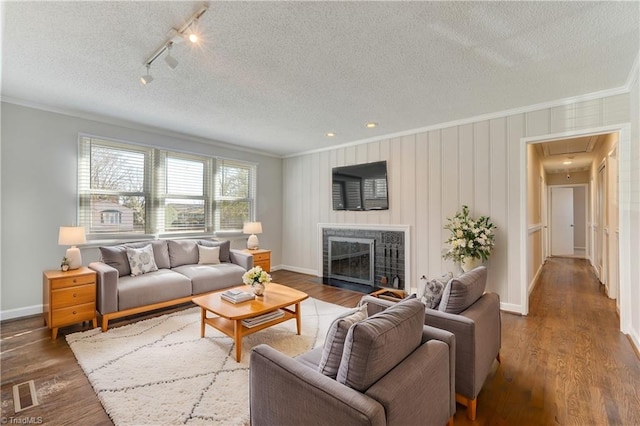 living room featuring a textured ceiling, ornamental molding, track lighting, and dark hardwood / wood-style floors