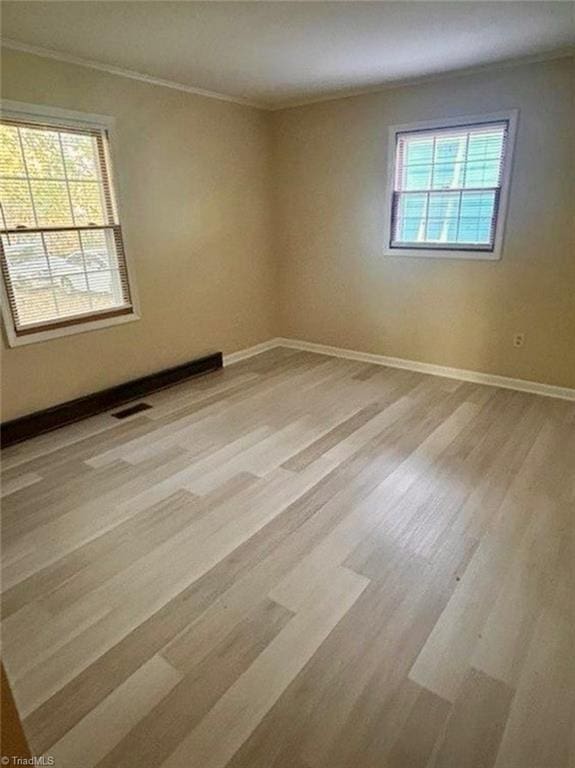 spare room featuring light wood-style floors, visible vents, and plenty of natural light