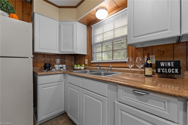 kitchen featuring a sink, freestanding refrigerator, and white cabinetry