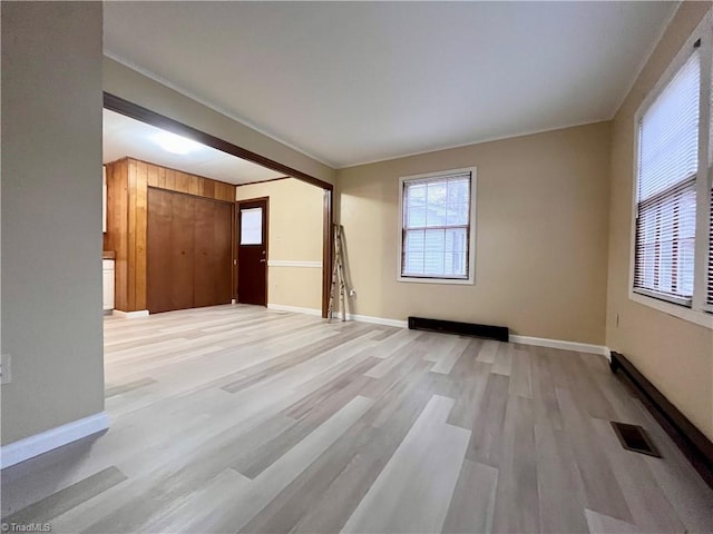 unfurnished room with light wood-type flooring, visible vents, and baseboards