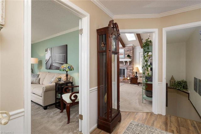 hall with ornamental molding, light hardwood / wood-style floors, and a skylight