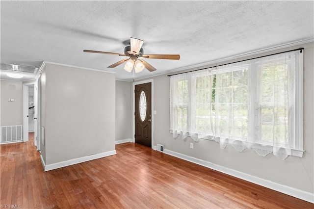 entryway with ceiling fan, a textured ceiling, wood finished floors, baseboards, and crown molding