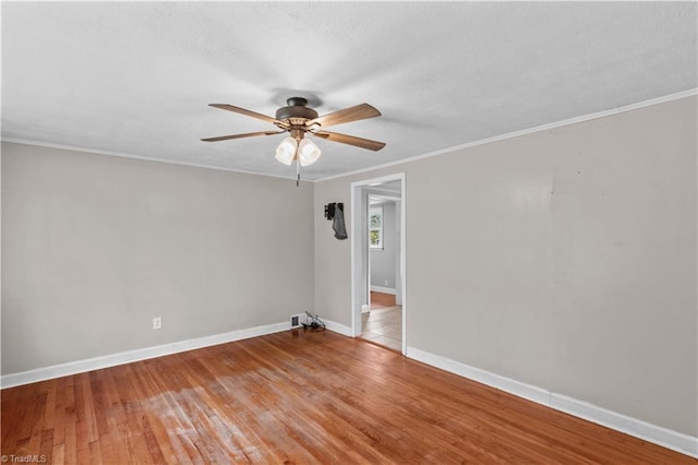 spare room featuring a ceiling fan, baseboards, light wood finished floors, and crown molding