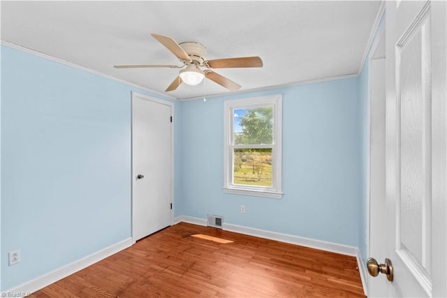 unfurnished room featuring wood finished floors, baseboards, crown molding, and a ceiling fan